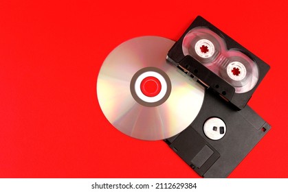 Audio cassette, floppy disk and disc on a red background. Legacy technologies
