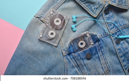 Audio Cassette And Headphones In The Pocket Of A Hipster Jeans Jacket On A Blue Pink Cream Color Background. Entertainment 80s. With Music In Life.