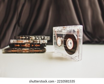audio cassette and stack of cassettes on table against dark background 