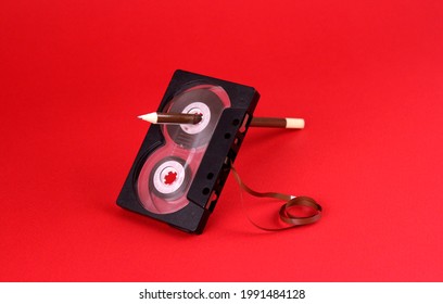 Cinta de audio con lápiz en ranura de rebobinado en fondo rojo