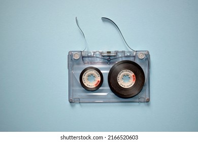 Audio cassette with torn tape on a blue background, top view. - Shutterstock ID 2166520603