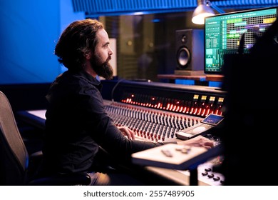 Audio engineer operating pc software for mixing and mastering tracks in studio, editing songs on control desk board. Music producer creating records with sliders and buttons, post production.