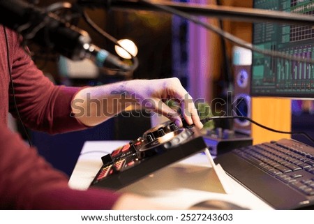 Audio engineer twisting pre amp knobs to edit tunes in post production, working with stereo equipment and mixing console. Young musician recording new music in his home studio. Close up.