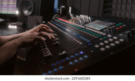 Audio engineer uses mixing console, remote control for adjusting sound, audio mixer. Musician changes the volume level, creates song with modern equipment. Sound recording studio. Music production. - Powered by Shutterstock