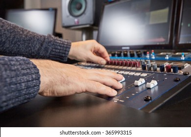Audio equipment and computer monitors in a sound studio with hands of the music producer on the mixing desk