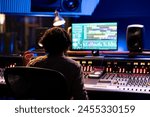 Audio expert working on editing music with daw software interface, processing and mixing sounds in control room. Skilled engineer operating on control panel board console, mixer station.