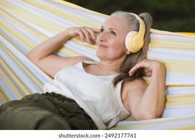 Audio healing. meditation. Slow life. Enjoying the little things. lifestyle portrait senior woman  with gray hair in headphones listens to music rests. - Powered by Shutterstock