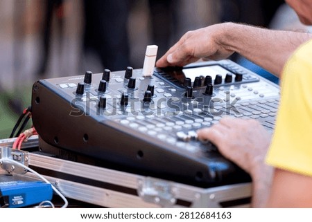Audio technician adjusting faders and knobs on a soundboard for music production or live performance