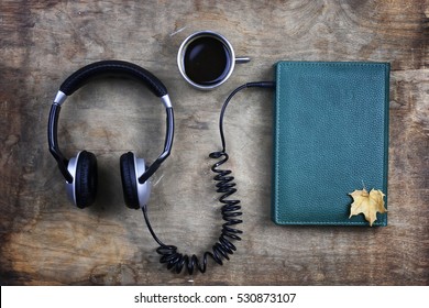 Audiobook Headphones And Book On A Wooden Table