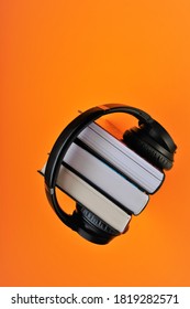 Audiobooks concept.Learning, knowledge and hobby.Paper book  set  with headphones on bright orange background.listening to audiobooks.