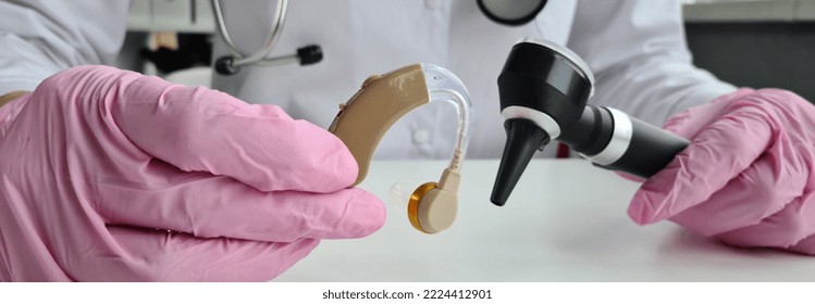 Audiologist Consultation Treatment Of Deafness. ENT Doctor With Otoscope In Hands Sits In Audiology Room During Consultation Concept