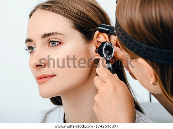 Audiologist doctor doing an ear\
exam with an otoscope to a patient woman. Audiology. Hearing\
test