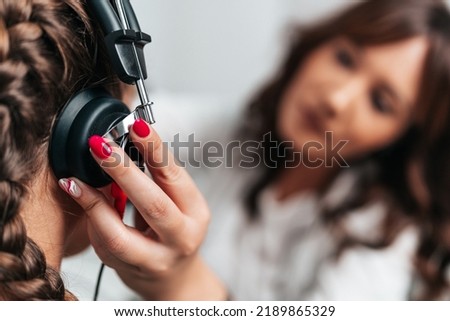 Audiologist doing impedance audiometry or diagnosis of hearing impairment. An beautiful teenage girl getting an auditory test at a hearing clinic. Healthcare and medicine concept. Close up shot.
