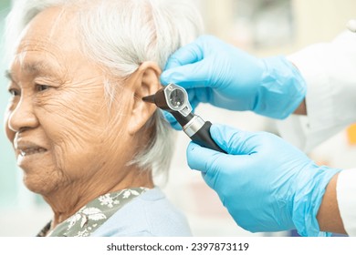 Audiologist or ENT doctor use otoscope checking ear of asian senior woman patient treating hearing loss problem. - Powered by Shutterstock