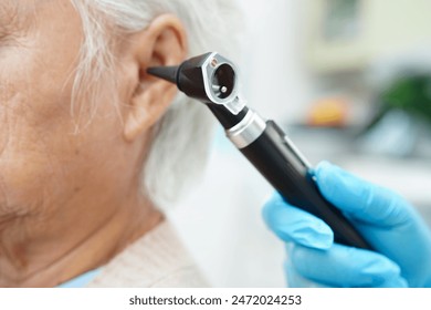 Audiologist use otoscope checking ear of elderly woman patient treating hearing loss problem. - Powered by Shutterstock