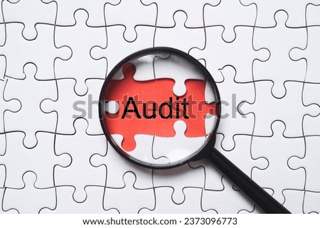 Audit wording with magnifier glass on red background among white jigsaw for quality control assurance and ISO concept.