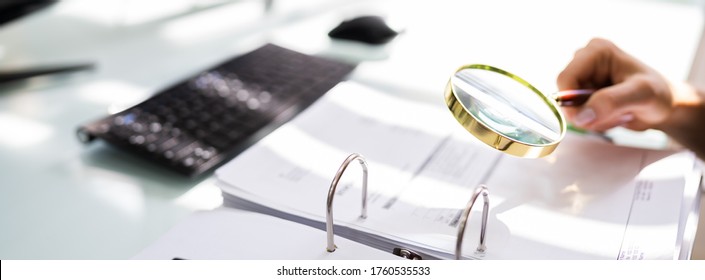 Auditor Investigating Corporate Fraud Using Magnifying Glass - Shutterstock ID 1760535533