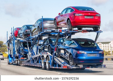Aug 10, 2019 Burlingame / CA / USA - Car transporter carries Tesla Model 3 new vehicles on a freeway in San Francisco bay area, back view of the trailer; 