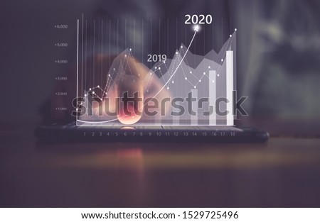 Augmented reality (AR) financial charts showing growing revenue In 2020 floating above digital screen smart phone, businesswoman having meeting about strategy for growth and success 