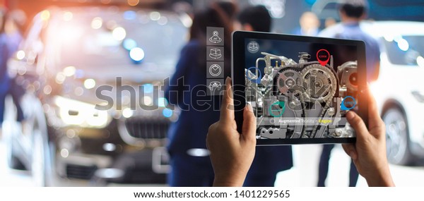 Augmented\
reality concept. AR. Industrial 4.0 , Hand of engineer holding\
tablet using virtual AR service application to check the work of\
electric machine on car showroom\
background