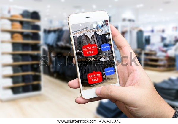 Augmented reality marketing concept.\
Hand holding smart phone use AR application to check number of\
social media like and sale price in retail fashion\
shop