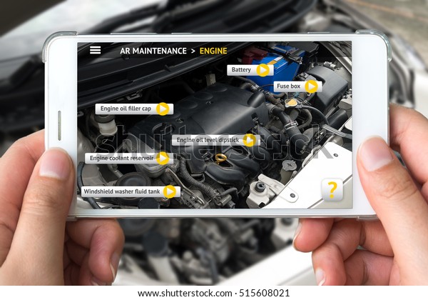 Augmented reality marketing concept. Hand\
holding smart phone use AR application to check maintenance car\
engine for customer.