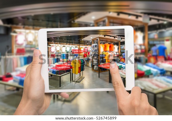 Augmented reality marketing concept. Hand\
holding digital tablet smart phone use AR application to check\
special sale price in retail fashion shop\
mall