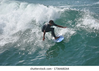 August 12, 2019. Young male surfer riding a wave on the shoreline of Huntington Beach in Orange County California, USA. 