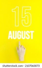 August 15th. Day 15 of month, Calendar date.Hand finger pointing at a calendar date on yellow background.Summer month, day of the year concept