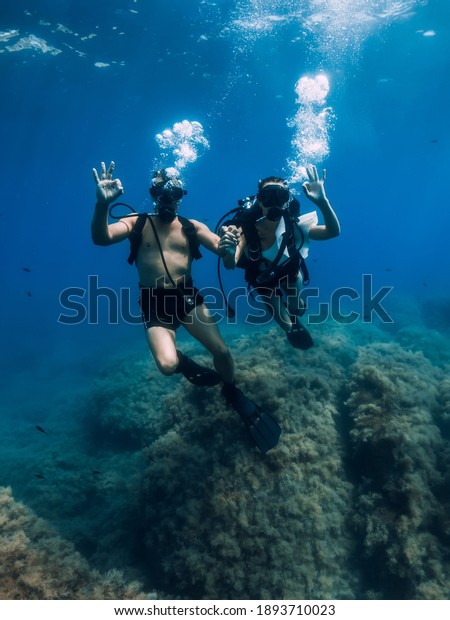 August 20,\
2020. Anapa, Russia. Couple of scuba divers glides underwater in\
transparent blue sea. Scuba diving in\
ocean