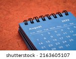 August 2022 - spiral desktop calendar against red mulberry paper, time and business concept