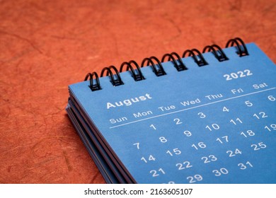 August 2022 - spiral desktop calendar against red mulberry paper, time and business concept