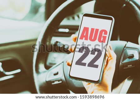 august 22nd. Day 22 of month,Calendar date. Month and day placed on a smartphone screen in womans hand in car interior. artistic coloring.  summer month, day of the year concept