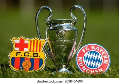 August 27, 2021 Barcelona, Spain. The Emblems Of Football Clubs FC Barcelona And FC Bayern Munich And The UEFA Champions League Cup On The Green Lawn Of The Stadium