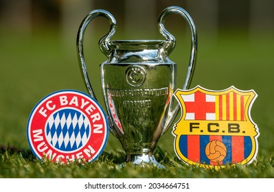 August 27, 2021 Bavaria, Munich. The Emblems Of Football Clubs FC Barcelona And FC Bayern Munich And The UEFA Champions League Cup On The Green Lawn Of The Stadium.