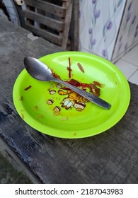  August 6, 2022. Sidoarjo. Indonesia. Close Up Photo, A Plastic Plate And A Tablespoon, Dirty And Unwashed, Are On The Fence On The Terrace Of The House.