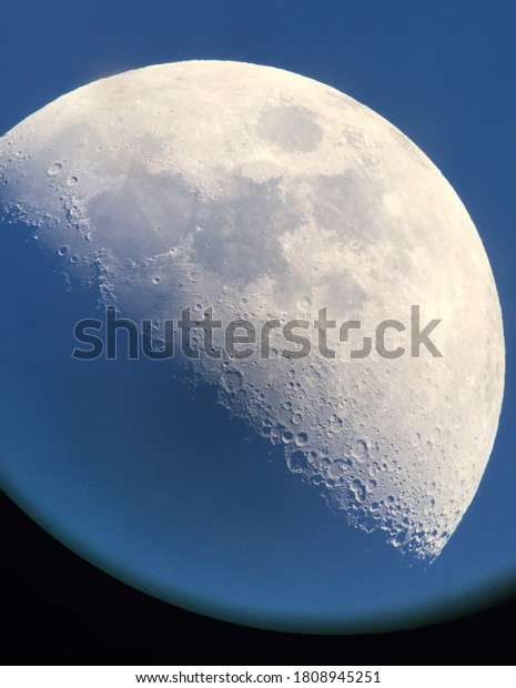 An August first quarter Moon as seen\
through a telescope with detailed craters and\
mares