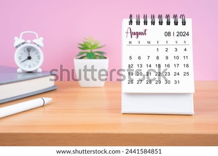 August Mini desk calendar for 2024 year on worktable with pink background.