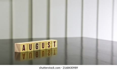 AUGUST Word On Wooden Cube On Black Gloss Wooden Table. Selected Focus