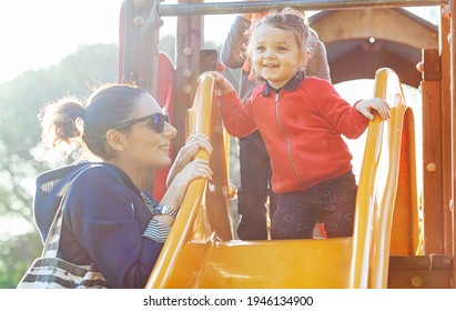 Aunt and nephew play on the slide at the park in a spring day. - Shutterstock ID 1946134900