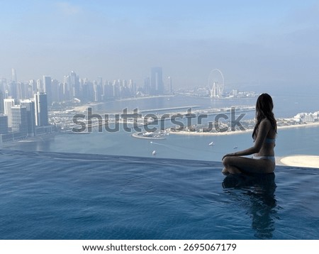 Aura skypool view, infinity pool, a woman sits by the edge, taking in the breathtaking view of the city and the ocean
