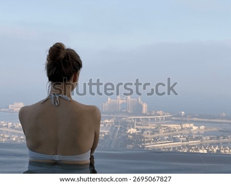 Aura skypool view, infinity pool, a woman looks out over the city of Dubai from the edge of an infinity pool, enjoying the beautiful scenery