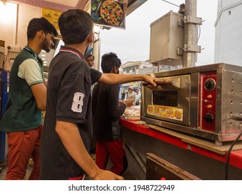 Aurangabad, Maharashtra,India-03-28-2021-Face Mask Wearing Boy Is Making Pizza In Pizza Oven In His Shop During Corona-COVID 19 Pandemic Spread, Post Lockdown.