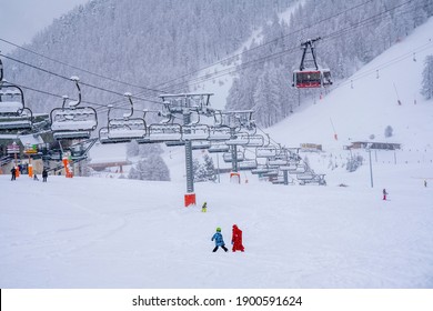 Auron, France - 01.01.2021: Downhill Skiing During A Heavy Snowfall. Professional Ski Instructors And Children On A Resort Slope In Mountains. Blurred Focus Background. High Quality Photo