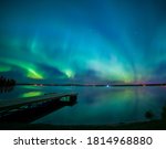 Aurora borealis dances of Baptiste Lake in Athabasca County with a dock. 