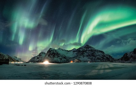 Aurora borealis or Northern lights over snow mountain on coastline in Flakstad, Lofoten islands - Shutterstock ID 1290870808