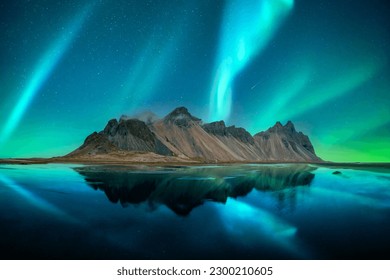 Aurora borealis Northern lights over famous Stokksnes mountains on Vestrahorn cape. Reflection in the clear water on the epic skies background, Iceland. Landscape photography - Shutterstock ID 2300210605