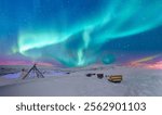 Aurora borealis (Northern lights) in the sky and many wooden snow sleds - Tromso, Norway