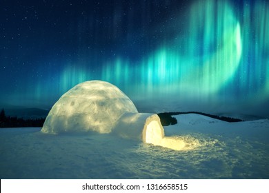 Аврора бореалис. Северное сияние в зимних горах. Зимняя сцена со светящимися полярными огнями и снежным иглу