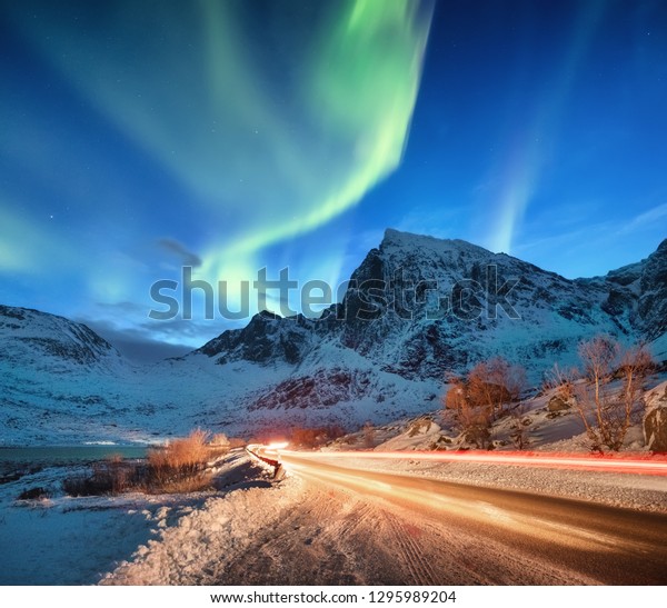 Aurora borealis\
on the Lofoten islands, Norway. Road traffic and blur car light.\
Green northern lights above mountains. Night sky with polar lights.\
Natural background in the\
Norway